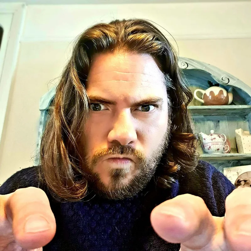 M.A. Knights frowning sternly and pointing both fingers straight at the camera